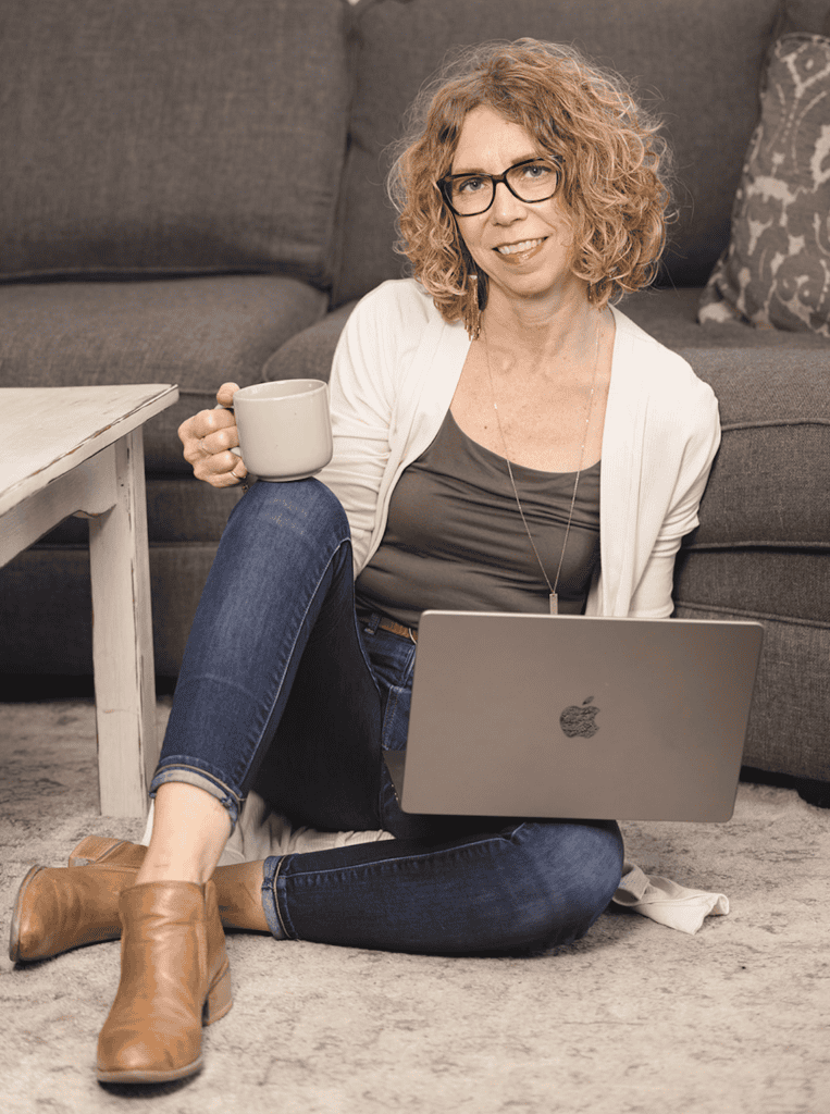 A lady on her laptop holding a cup of coffee learning how to set work boundaries.